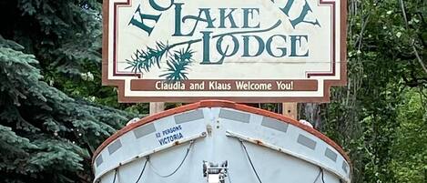En båt med en skylt ovanför som visar texten ”Kootenay Lake Lodge” och ”Claudia och Klaus hälsar er välkomna!”.