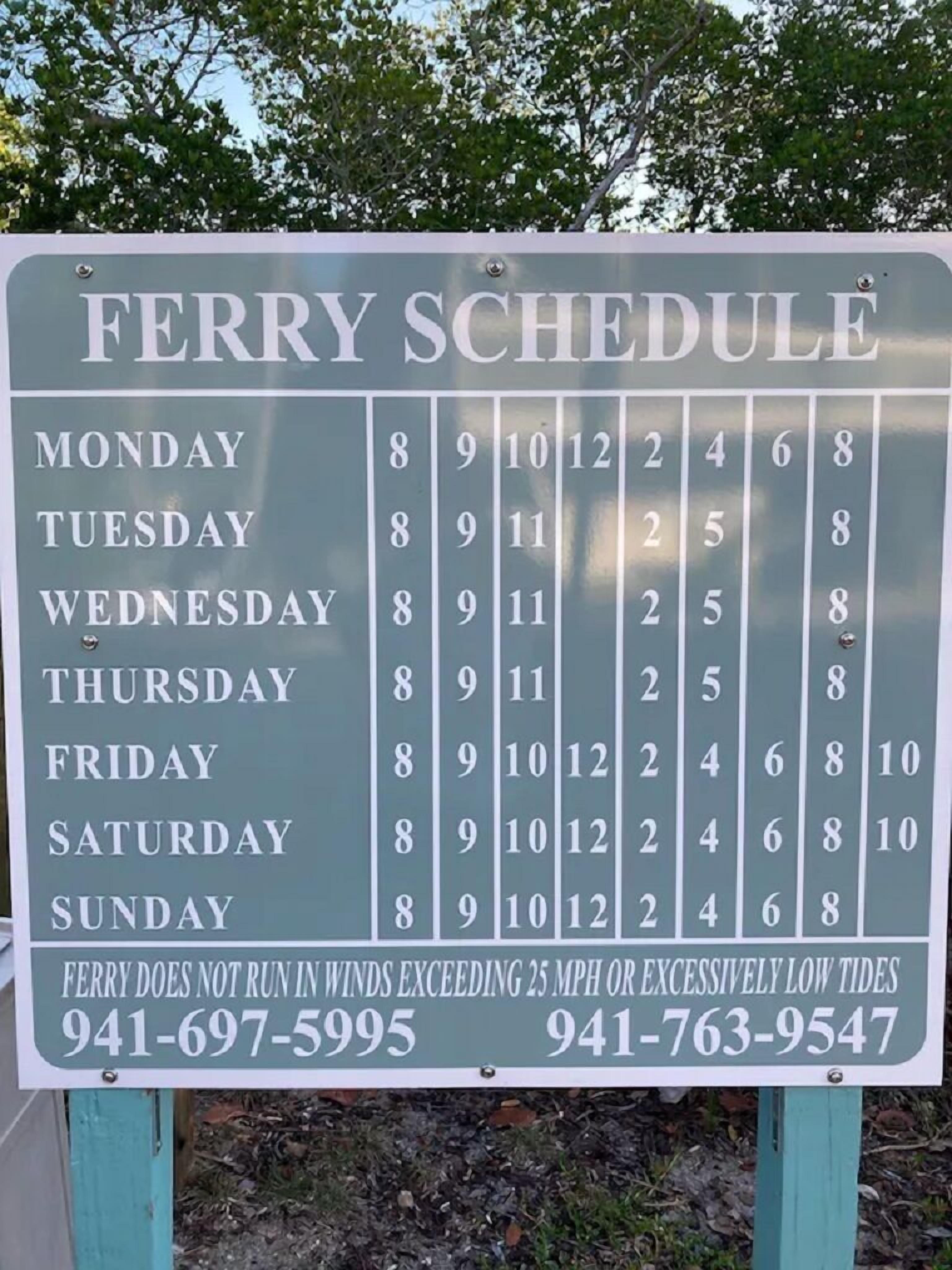 A ferry schedule sign with operating times and contact numbers.