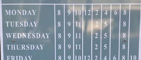 A ferry schedule sign with operating times and contact numbers.