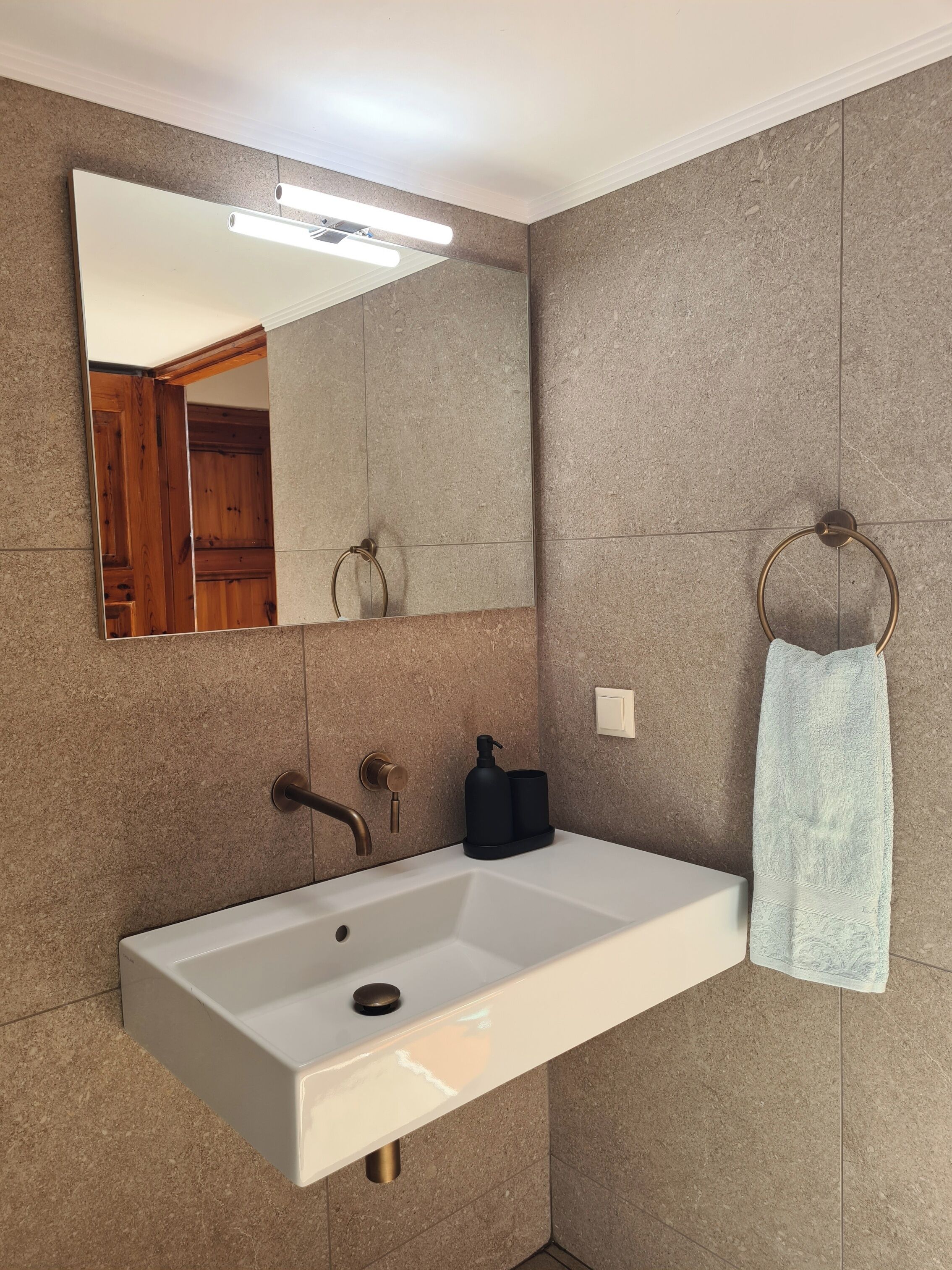Une salle de bain avec un lavabo blanc, un miroir et un porte-serviette.