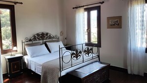 Un dormitorio con estructura de cama de madera, una mesita de noche y una ventana con cortinas.
