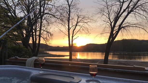 A view from a window overlooking a lake at sunset with trees and a hammock. - Quietwater Cottage-On Water/Nature/Hiking/Relaxing/ Hot Tub & Sauna, Peaceful! (Poynette)