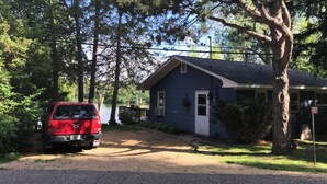 A small blue house with a white door, a red truck parked in front, and a tree to the right. - Quietwater Cottage-On Water/Nature/Hiking/Relaxing/ Hot Tub & Sauna, Peaceful! (Poynette)