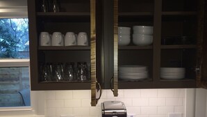 A kitchen with white tiled backsplash, a coffee maker on the counter, and shelves with cups and plates. -  Wonderful 2/1 in Bouldin area.Walk to food trailers, Zilker and Barton Springs! (Austin)