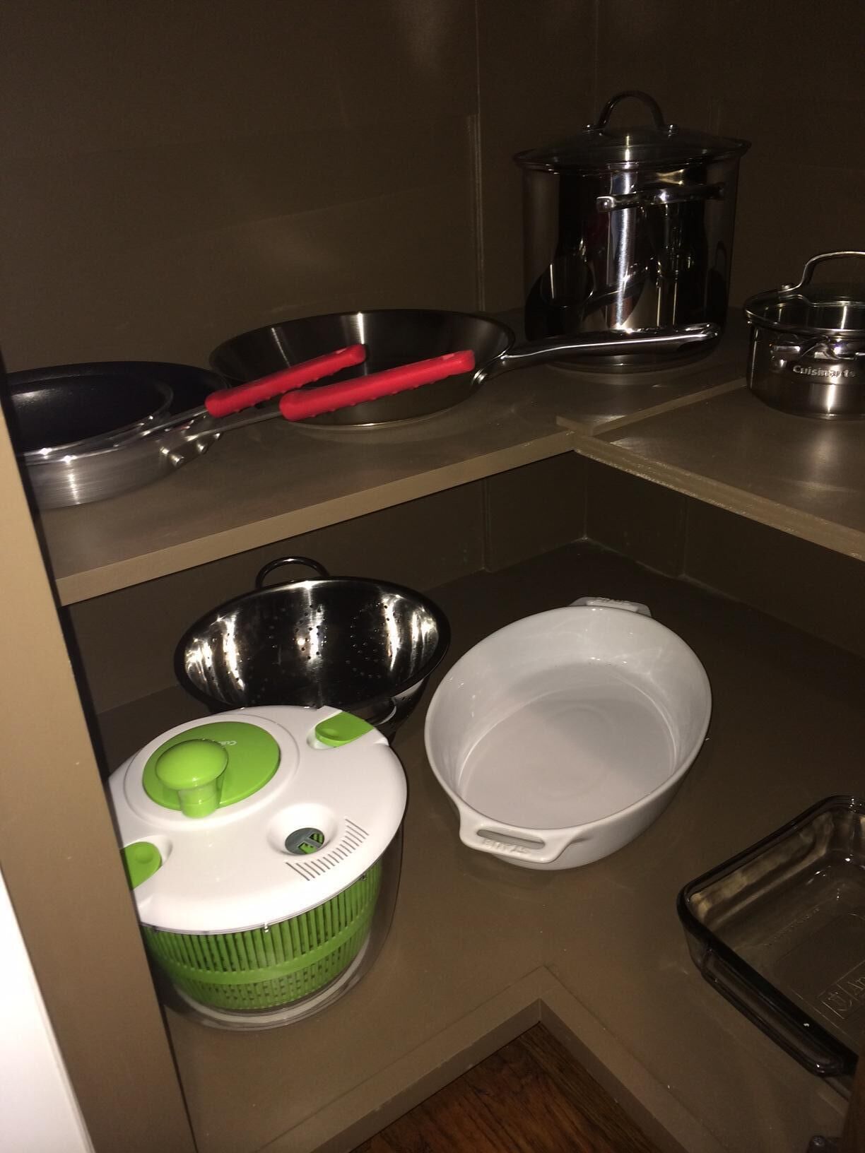 Ett kök med köksredskap i rostfritt stål, en vit skål, en grön och vit apparat samt ett svart bricka.