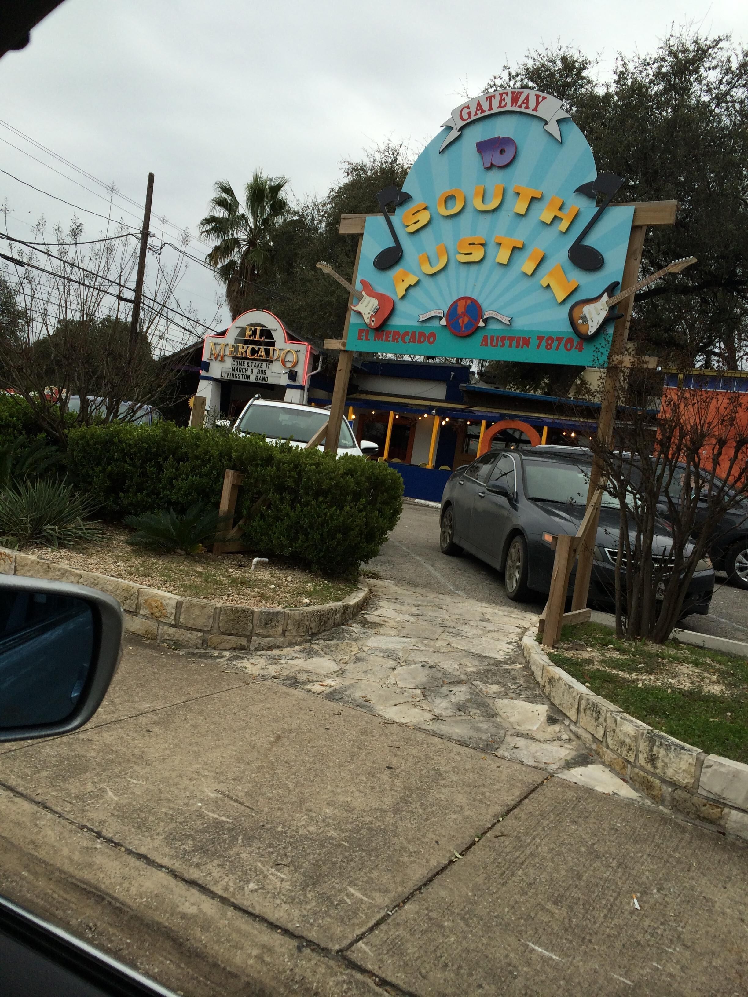 A sign for 'South Austin' with a guitar and a market symbol, indicating a music venue or bar.