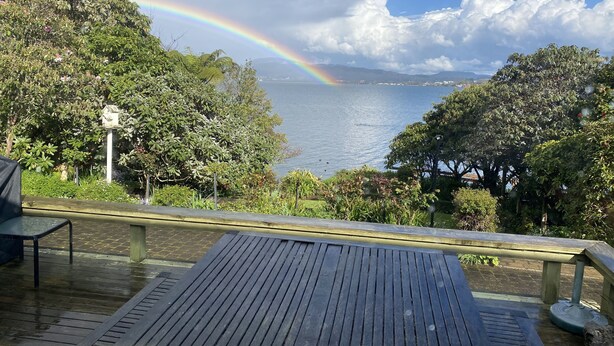 Una terraza de madera con vista a un lago y un arcoíris.