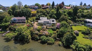 Zona residencial con una casa grande rodeada de exuberantes jardines y un lago.