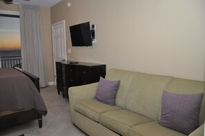 A room with a bed, a sofa, a TV mounted on the wall, and a window with curtains. - Oceanfront Luxury 6th Floor Splash Resort: 2BR/2BA King Unit, Free Beach Service (Panama City Beach)