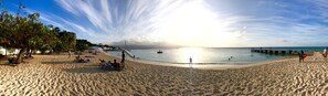 A beach with people sunbathing, a pier, and a clear sky. - Serene Flat, 1 bedroom apartment (Montego Bay)