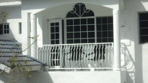 Un edificio bianco con un balcone, una finestra con decorazioni e un tetto in tegole.