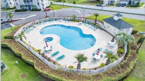 Eine Vogelperspektive auf einen Swimmingpool, umgeben von Liegestühlen und Palmen.