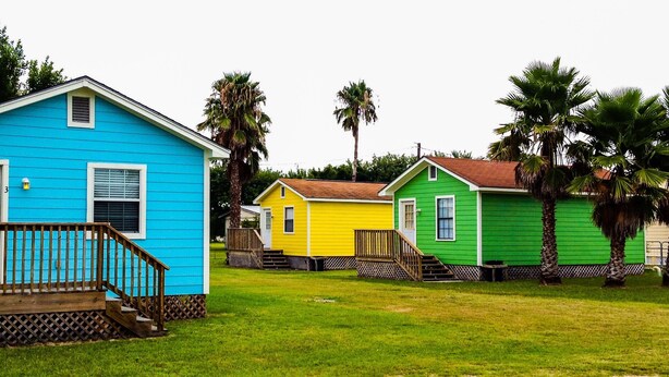 A row of colorful houses with a wooden deck and steps leading to the front door.