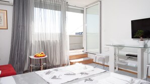 Une chambre d’hôtel avec un lit, une petite table avec des fruits, une télévision et un bureau en verre.