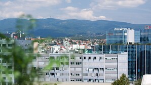 Un paysage urbain avec des bâtiments modernes, dont un imposant gratte-ciel en verre orné d’une enseigne.