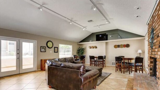 A spacious living room with a brown leather couch, a dining area with wooden chairs, and a brick fireplace. - Bright and Peaceful condo 2 bedrooms  2 bath comfortable clean Great location! (Phoenix)