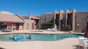 A pool area with lounge chairs and a building with a red roof in the background. - Bright and Peaceful condo 2 bedrooms  2 bath comfortable clean Great location! (Phoenix)