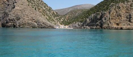 Un paysage côtier caractérisé par des eaux turquoise limpides, des falaises rocheuses et une petite plage.