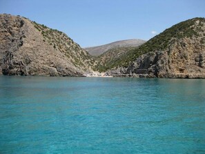 Eine Küstenlandschaft mit klarem türkisblauem Wasser, steinigen Klippen und einer kleinen Strandbucht.