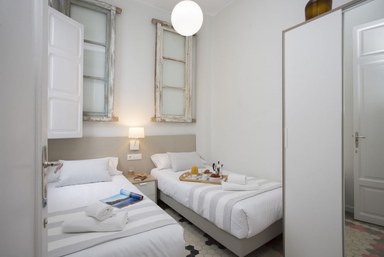 Une chambre d’hôtel avec deux lits, une armoire, une table de chevet avec une lampe et une fenêtre donnant sur un beau paysage.