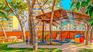 A playground with a covered play area, benches, and a red playhouse.