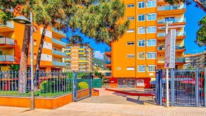 A multi-story residential building with balconies, a gated entrance, and a paved walkway.