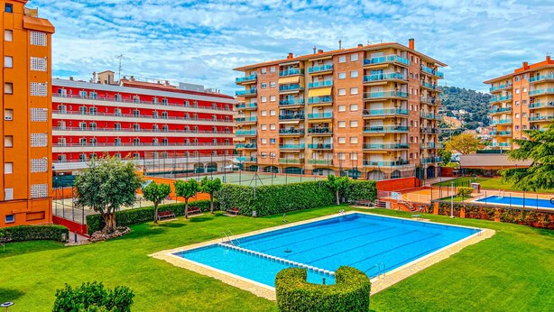 A hotel with multiple floors, a swimming pool, and a well-maintained lawn.