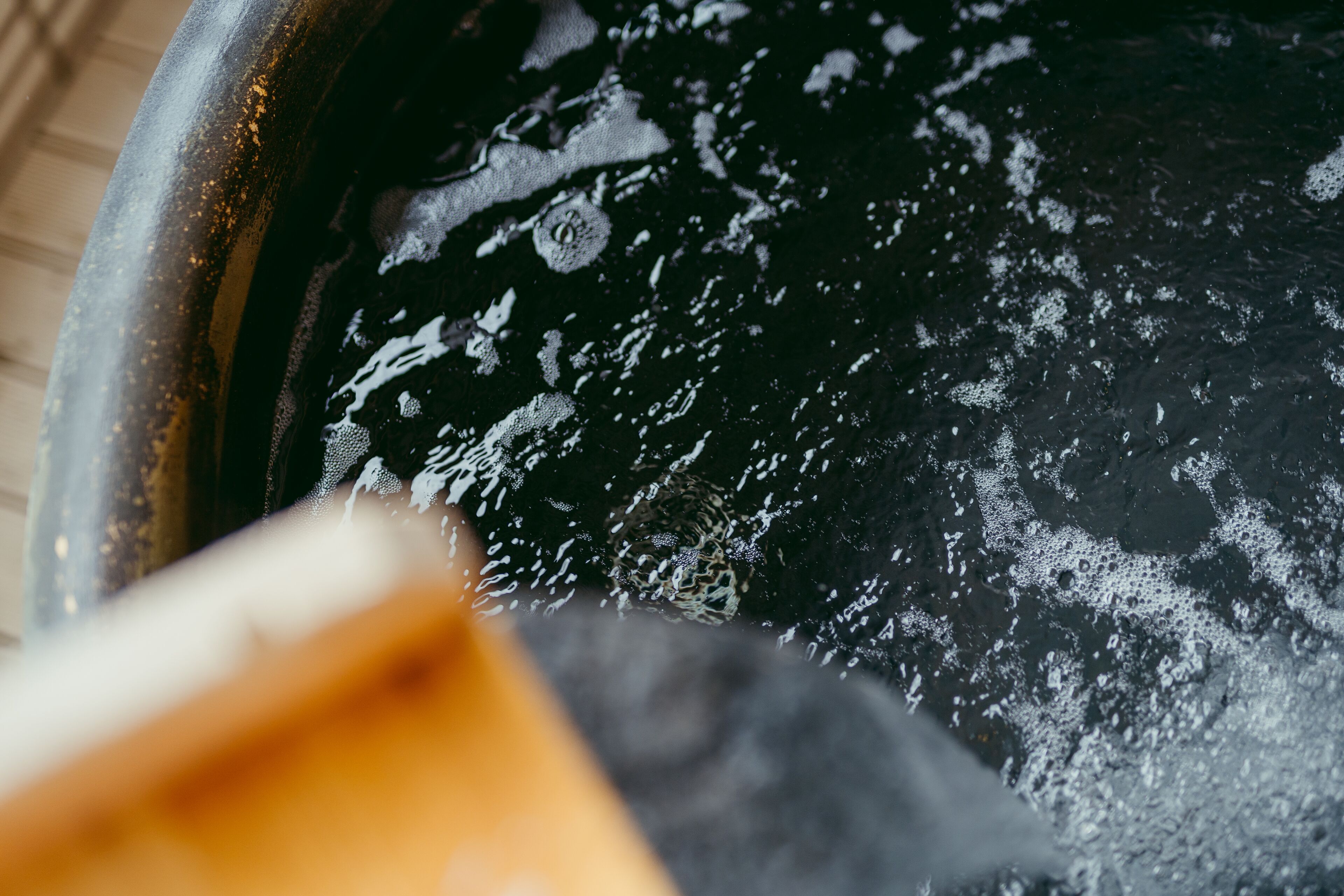 A close-up of a black pan with a white substance, possibly soap or paint, and a wooden spatula.
