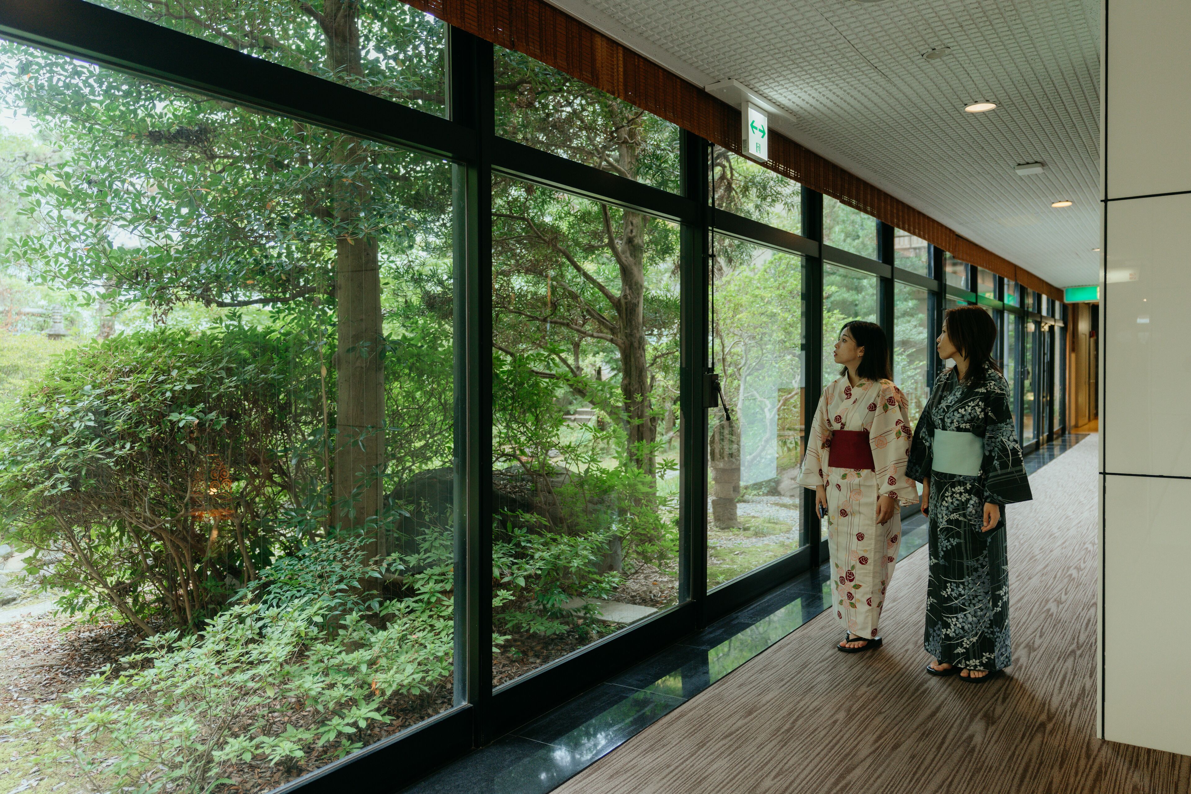 A corridor with large windows overlooking a lush garden.
