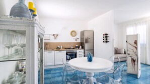 A modern kitchen with white cabinets, a stainless steel refrigerator, and a dining area with a white table and clear chairs. - House with terrace, 80 metres from beach of San Vito lo Capo, Sicily (San Vito Lo Capo)