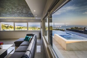 Un salon moderne doté d’une grande fenêtre donnant sur une piscine et offrant une vue panoramique.