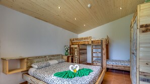 Ein Schlafzimmer mit einem Holzbettgestell, einem Einzelbett mit einem herzförmigen Handtuch und einem kleinen Nachttisch mit einer Pflanze.