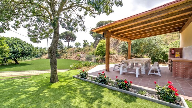 Eine Terrasse mit Pergola, Gartenmöbeln und Grillplatz.