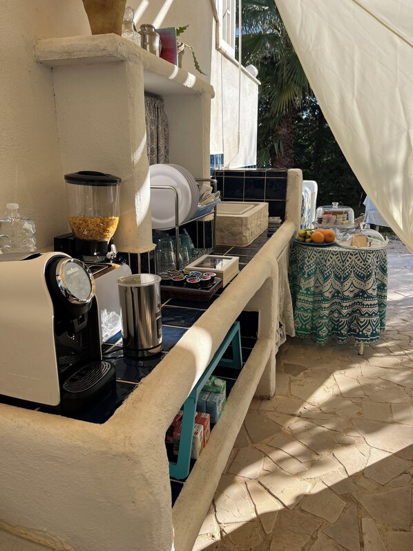 A kitchen area with a coffee machine, a blender, and a dish rack. There is a table with a patterned tablecloth and a cake on a stand. - Villa Méditerranée with parking space (trani)