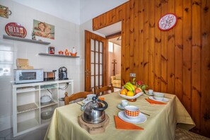 Enjoy a warm meal in this inviting dining area, complete with a table set for a meal, a teapot, and a bowl of fresh fruit.