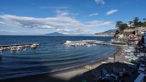 A coastal town with a pier, boats, and a mountain in the background.