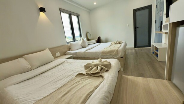 A hotel room with two beds, a small table, a mirror, and a door leading to a bathroom.