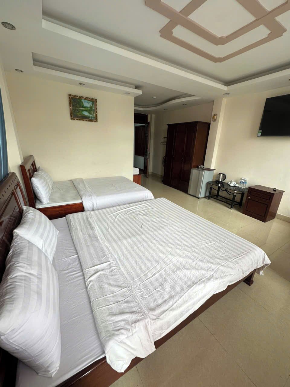 A hotel room with two beds, a desk, a chair, a television, and a wardrobe.