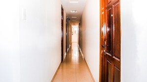A long, narrow hallway with wooden doors on one side and white walls on the other.