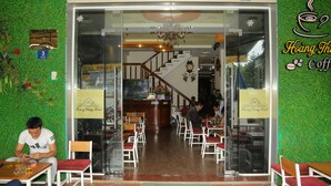 A hotel lobby with a staircase, wooden chairs, and tables.