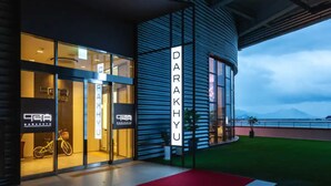 A modern building with a glass facade and a red carpet leading to the entrance. - DARAKHYU Yeosu Capsule Hotel by WALKERHILL (Yeosu)
