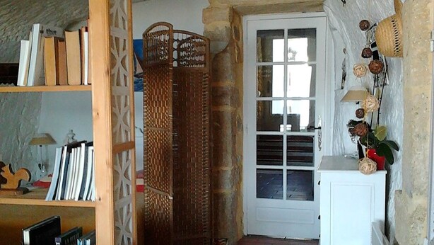 A cozy living room with a blue sofa, a bookshelf, and a wicker screen. A white cabinet with decorative items is visible in the background. - Unusual holiday in a troglodyte house in Saint-Chamas. (Saint-Chamas)