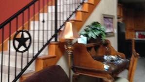A staircase with a black railing, a red wall with a star decoration, and a wooden chair with a cushion. - Beautiful Lakefront Home-Lake Alan Henry (Justiceburg)