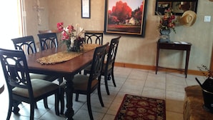 A dining area with a wooden table, chairs, a vase of flowers, a framed picture, and a small table with a hat and flowers. - Beautiful Lakefront Home-Lake Alan Henry (Justiceburg)