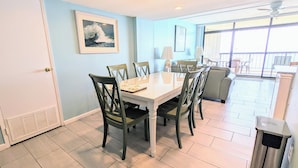 A dining area with a table and chairs, a ceiling fan, and a view of the outdoor balcony. - Direct Oceanfront Condo, Amazing Views of Ocean and Bay (Ocean City)
