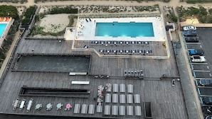 An aerial view of a hotel with a swimming pool, sun loungers, and a parking area. - Direct Oceanfront Condo, Amazing Views of Ocean and Bay (Ocean City)
