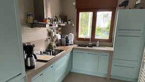 A kitchen with light blue cabinets, a stainless steel coffee maker, and a window providing natural light. - nice quiet house  (Quimper)
