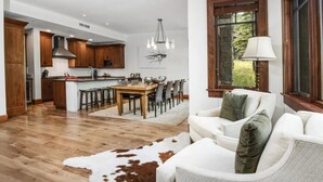 Una sala de estar moderna con un sofá blanco, un tapete de cuero de vaca y un comedor con una mesa y sillas de madera.