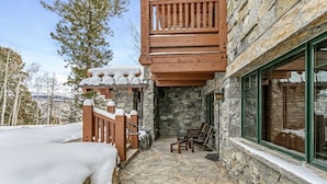 Un edificio de piedra con un balcón de madera y una escalera de piedra que conduce a una terraza de madera.