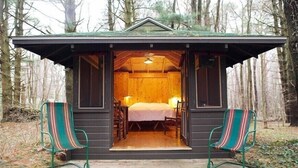 Een gezellig houten huisje met een bed, twee stoelen en een kleine tafel.